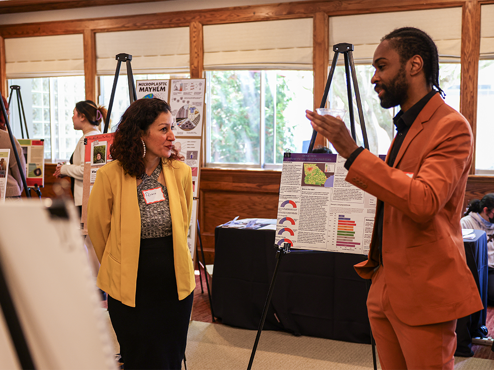 Two people chatting in front of a poster at the LCA showcase