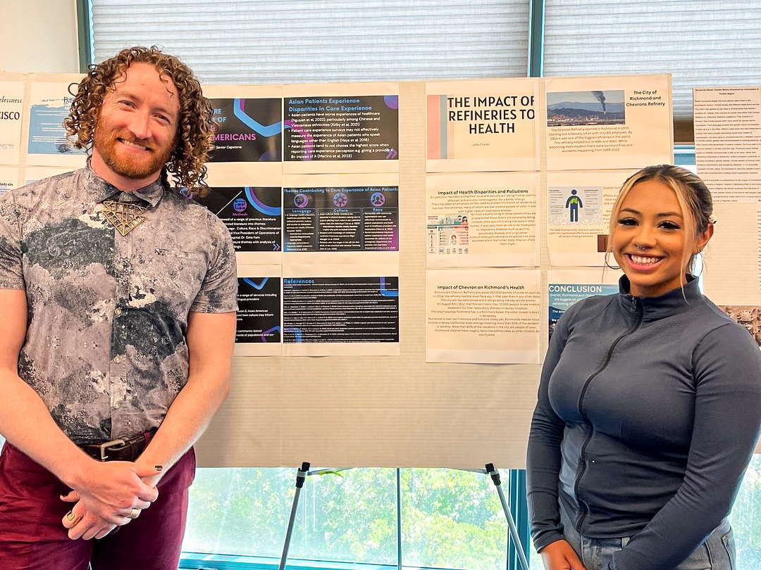 Two students smiling in front of their poster at the COES showcase